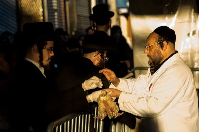 A worker hands a chicken to a kaporos practitioner in Williamsburg